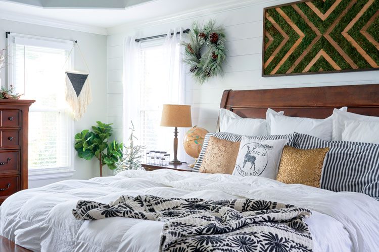 The master bedroom of their family friendly Christmas house has modern, minimalist wall decor like artificial plants and yarn hangings.