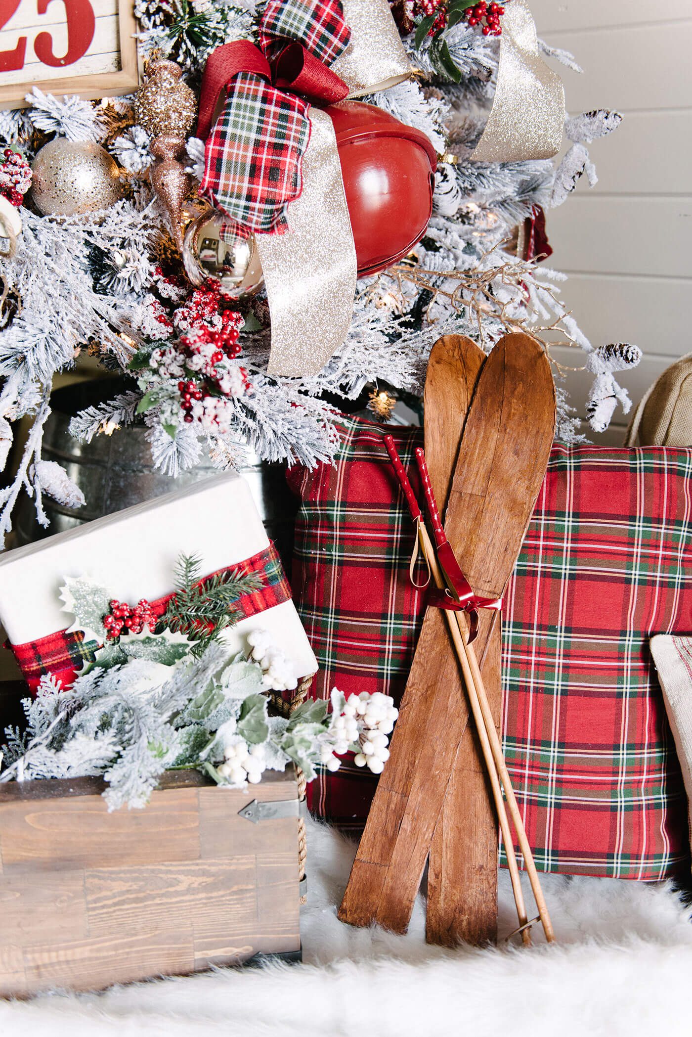 White gift wrap on packages with red embellishments under a Christmas tree