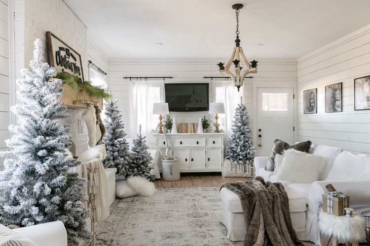 The living room of the white Christmas home, decorated with several snow-crusted pine trees.
