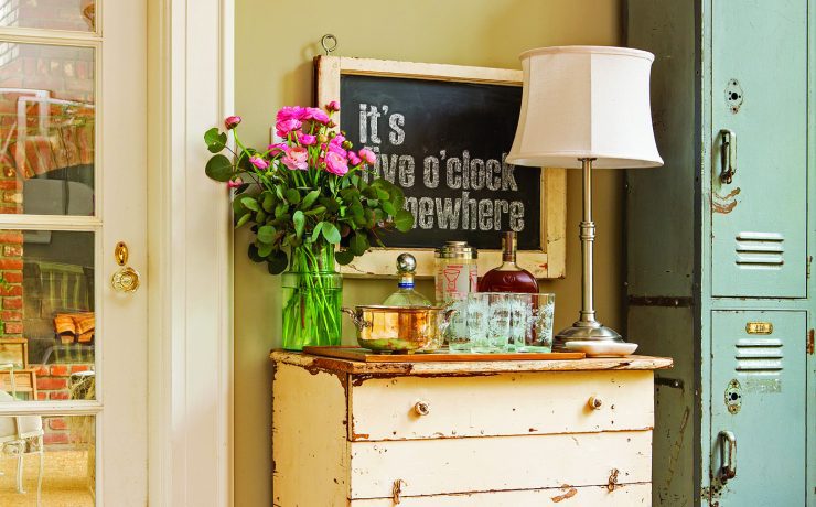 A cream-colored vintage desk with a lamp, bouquet of flowers and teal vintage lockers next to it demonstrates how to decorate with what you already have.