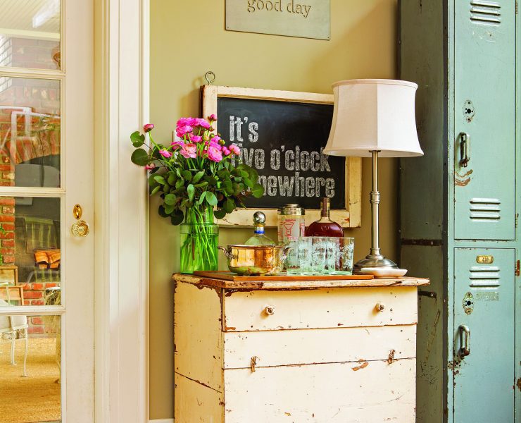 A cream-colored vintage desk with a lamp, bouquet of flowers and teal vintage lockers next to it demonstrates how to decorate with what you already have.