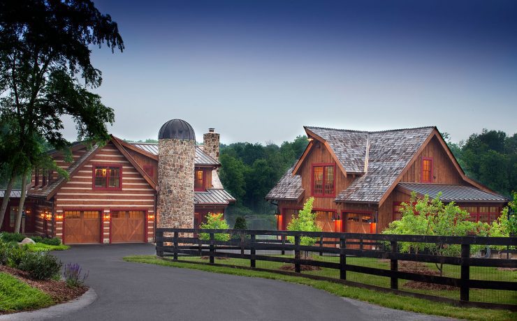 The exterior of two separate wooden farmhouse buildings, including a stone silo and a surrounding fence.