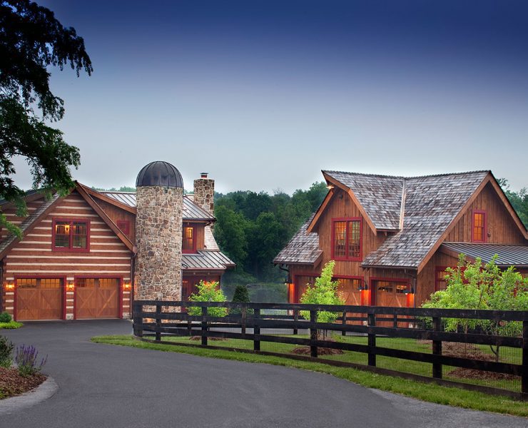 The exterior of two separate wooden farmhouse buildings, including a stone silo and a surrounding fence.