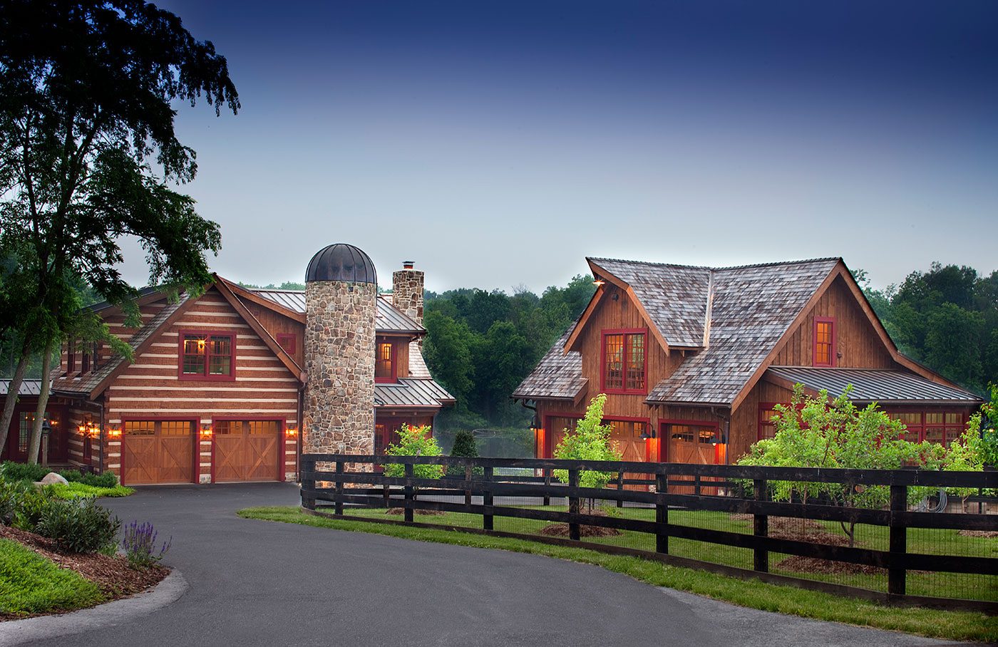 The exterior of two separate wooden farmhouse buildings, including a stone silo and a surrounding fence.