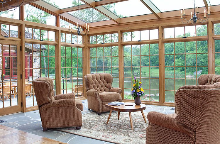 A sun room with vast windows contains three large chairs