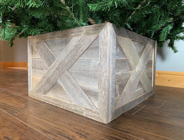 A natural wood crate in the style of barn doors with the Christmas tree standing in the middle of it.