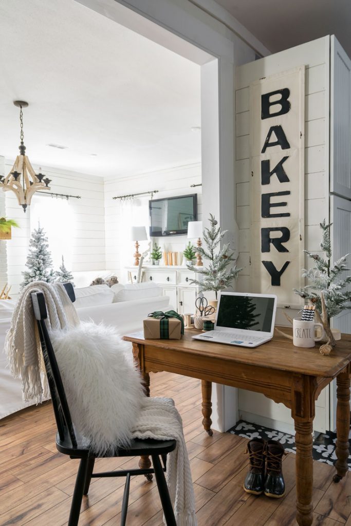 The wooden office desk next to the living room with a "Bakery" sign behind it in their white Christmas home.