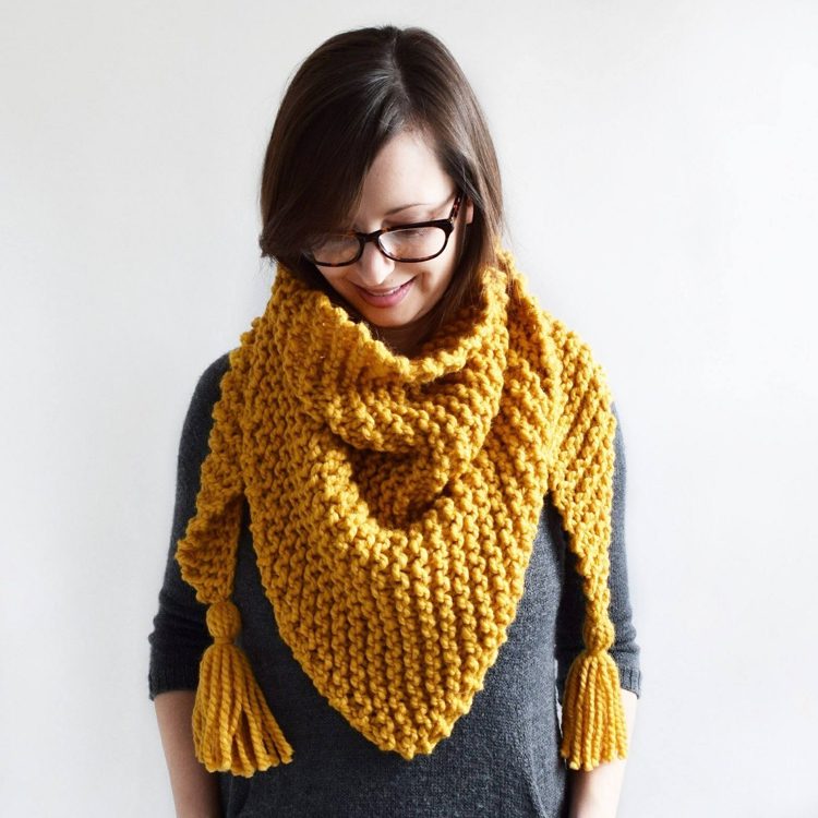 Knit in chunky farmhouse fashion, this mustard-colored scarf has two hassled ends.