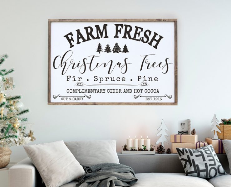 A large, rectangular black and white sign that says "farm fresh Christmas trees" in vintage-inspired fonts. It also includes words about hot cider and cocoa.