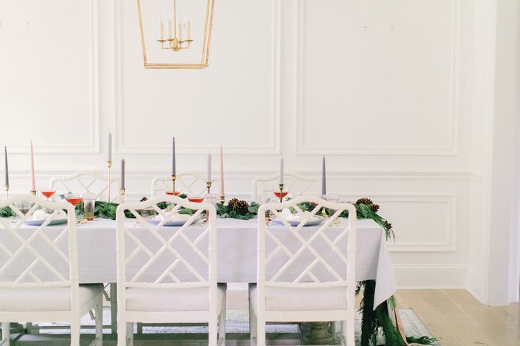 The dining room is simple with white walls, making the effect of the evergreen garland striking against the otherwise pale room.