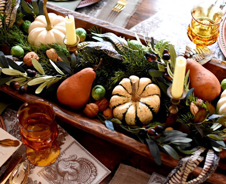 This fall tablescape is topped with a long, oval wood bowl filled with a full garland, gourds and rustic candlesticks.