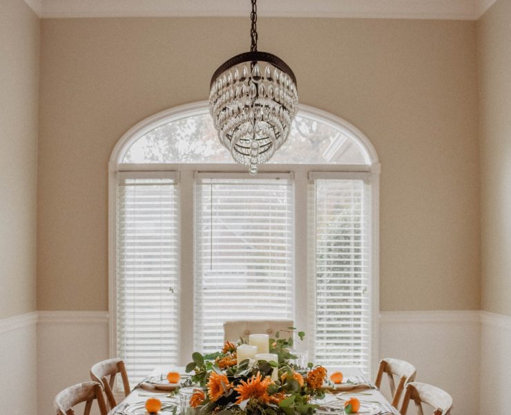 This fall tablescape includes an orange on each plate as well as oranges dotted throughout the center garland on the table.