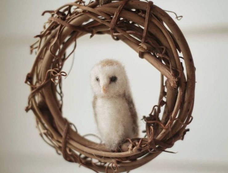 A barn owl sits in a grapevine wreath full of rustic Christmas charm