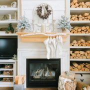 Fireplace with wood mantel, stockings and built-in shelves full of firewood.