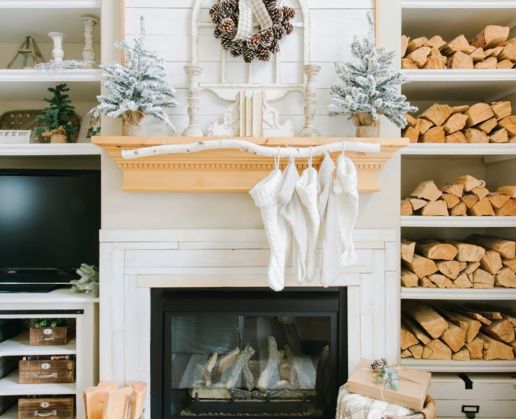 Fireplace with wood mantel, stockings and built-in shelves full of firewood.