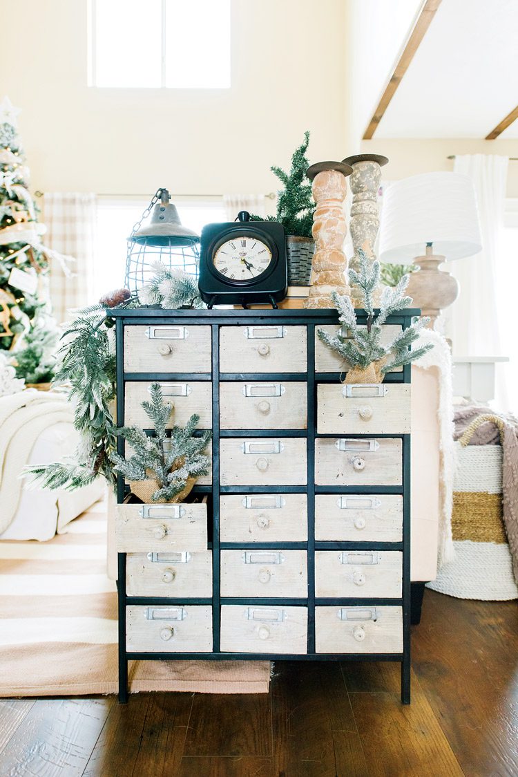 Vintage-inspired apothecary cabinet with light-colored drawers and black edges, decorated with neutral decor.