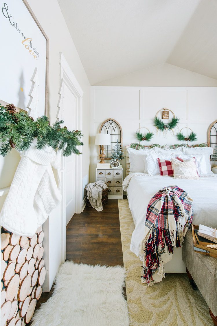 Master bedroom with faux fireplace, wreaths above the bed and red accents.