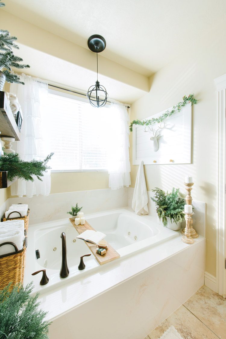 Large bath tub with wood tray across the tub and neutral/natural Christmas decor.