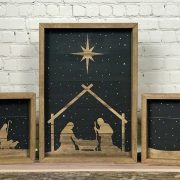 Nativity set of three wood pieces with a black background to make the silhouettes of the manger scene stand out.