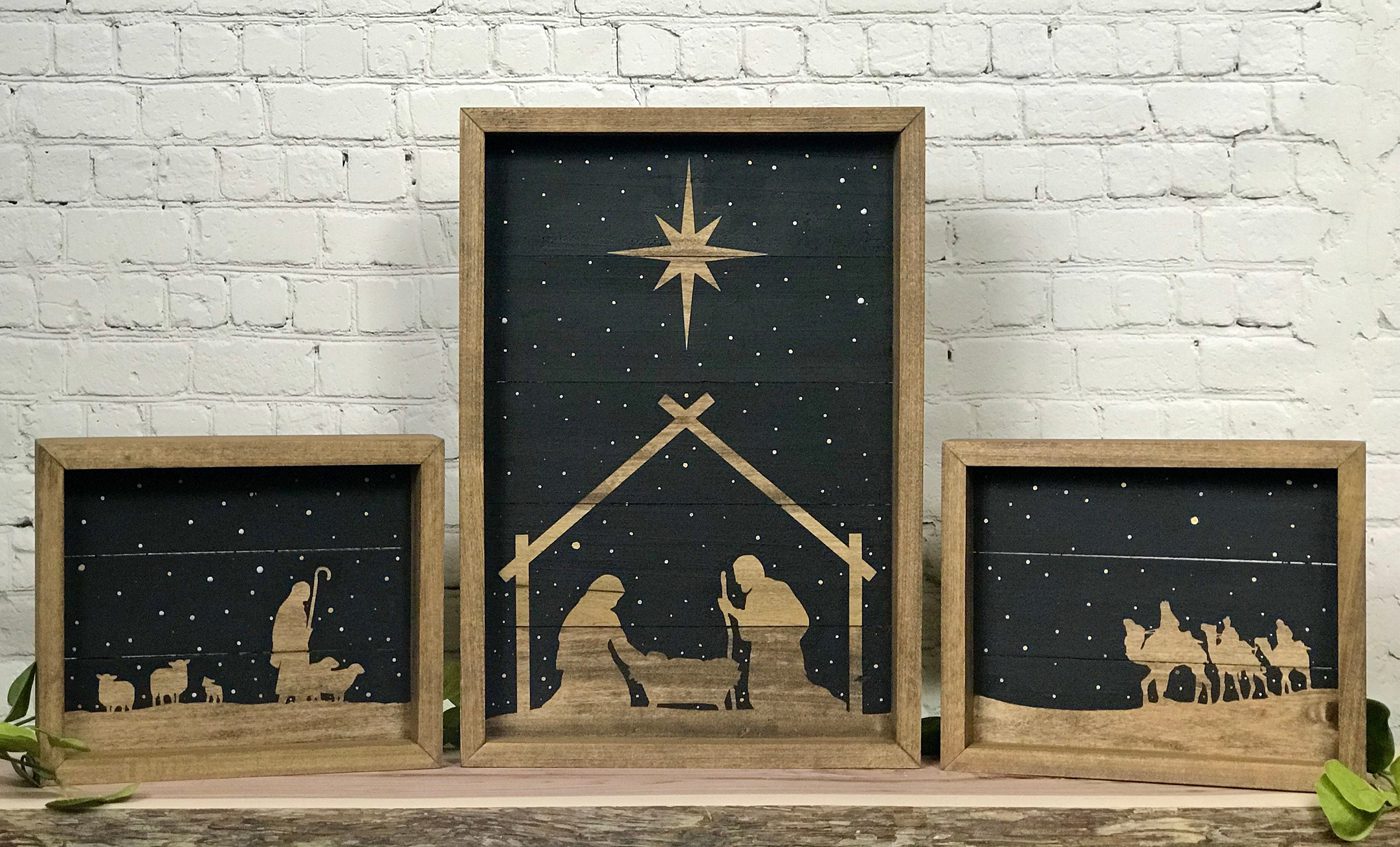 Nativity set of three wood pieces with a black background to make the silhouettes of the manger scene stand out.