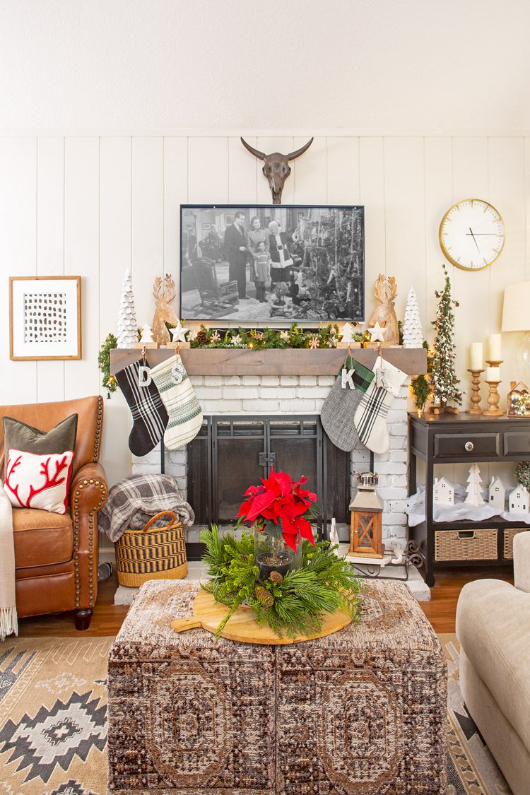 The Christmas cabin family room with stockings above the fireplace and neutral furniture/decor.