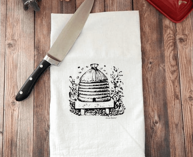 White kitchen towel with black honey bee hive illustration on the front.
