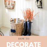 This farmhouse entryway shows how to decorate with an upcycled pair of rubber boots filled with fall branches and a black and white flannel short hanging from a wall hook.