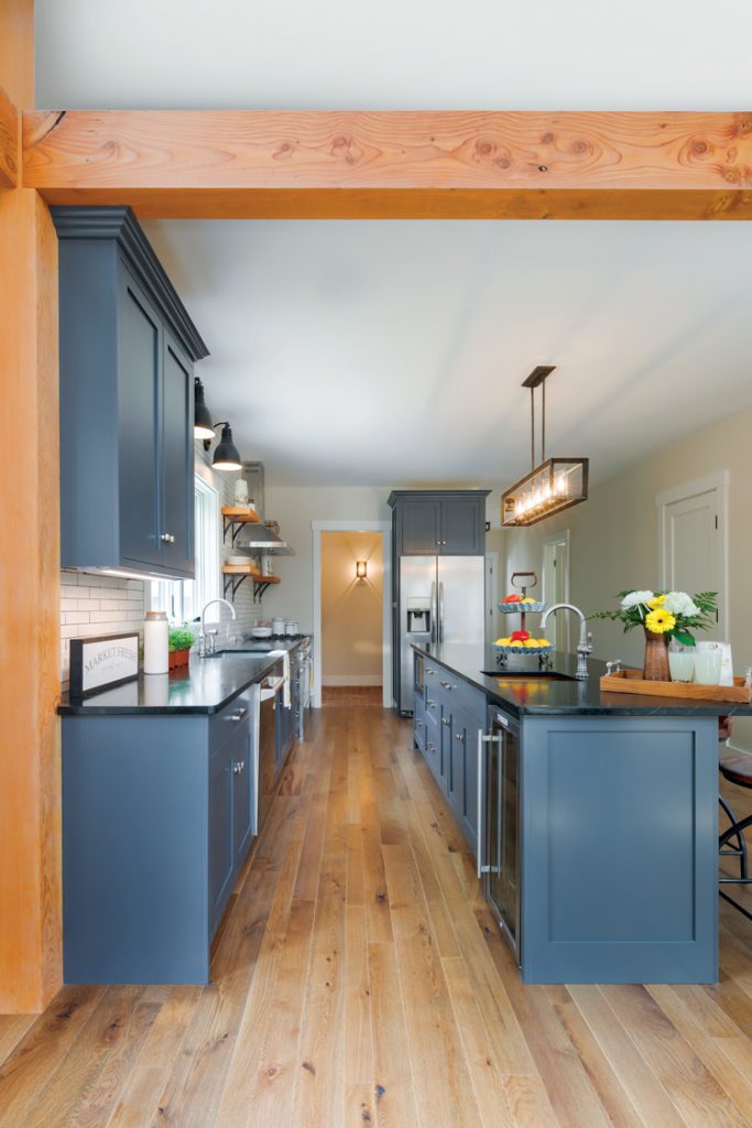 The kitchen has darker wood floors that perfectly complement the blue cabinets