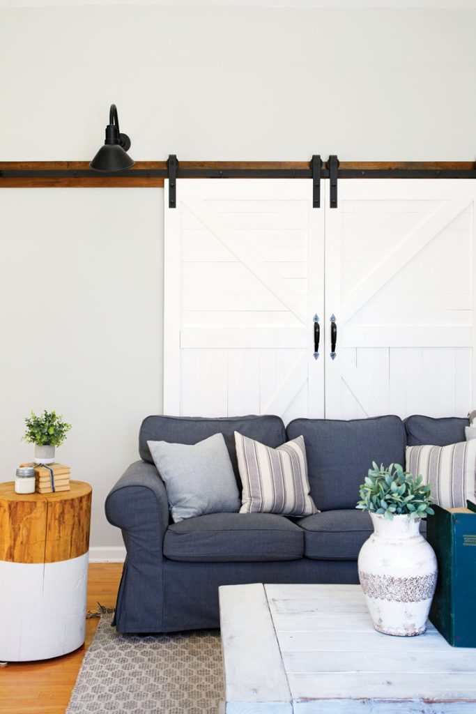 White sliding barn doors behind a modern blue couch in this modern farmhouse style home in connecticut