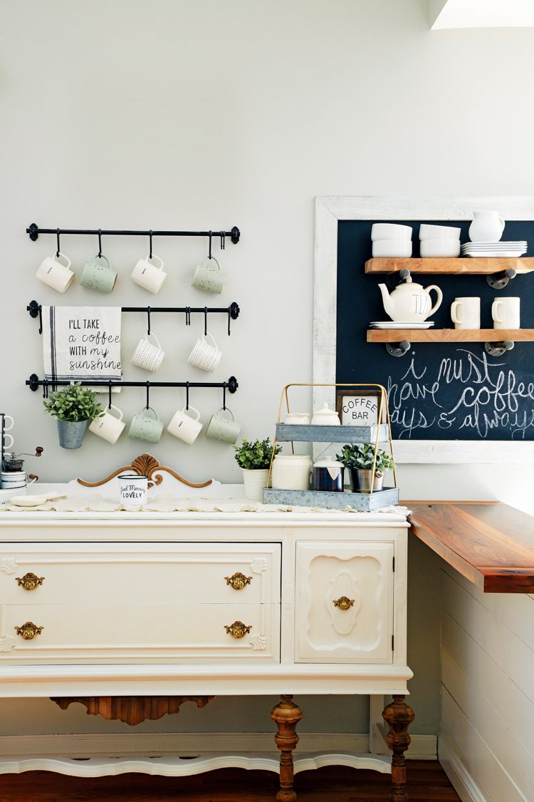 A white buffet cabinet transformed into a coffee bar on which cups and saucers sit.