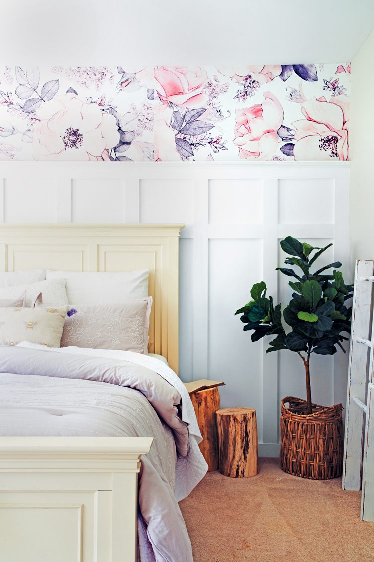 An off-white bedframe with eggshell bedding in a room with white 3d paneling designs.