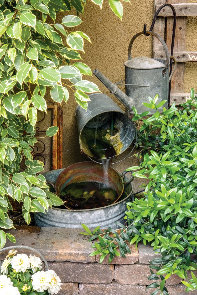 A feature of this vintage farmhouse, a fountain made from metal pails pouring into other pails