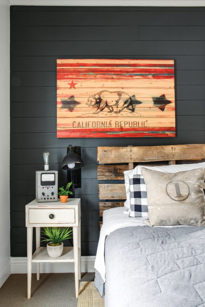 This vintage farmhouse also has a boys' room with dark shiplap and a picture of an unfinished California flag wood art