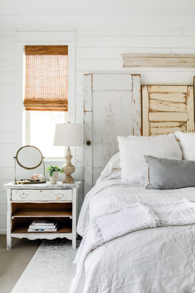 Behind the white bed is a headboard made from shippy vintage doors