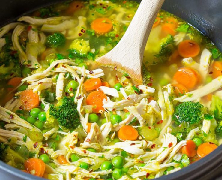 Pot of soup recipe with shredded chicken, peas, carrots and broccoli.