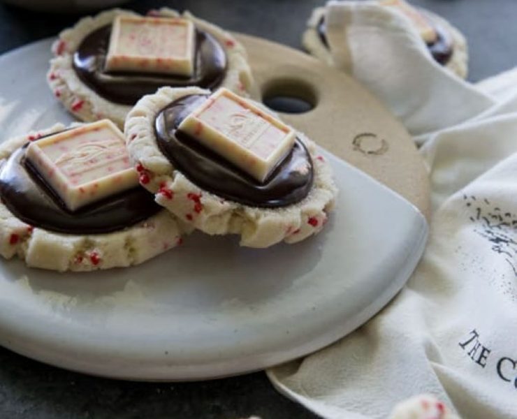 Chocolate peppermint bark sugar cookies with peppermint bark candy toppers surrounded by rich dark chocolate