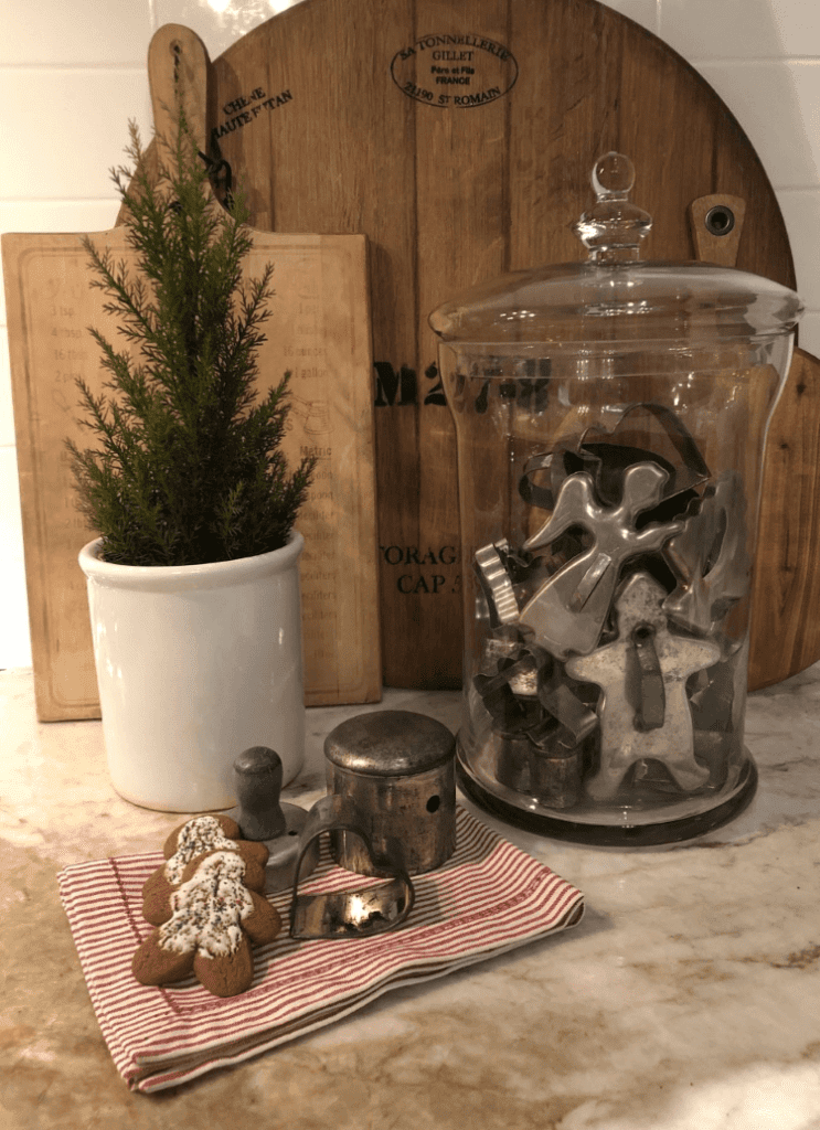 Vintage Christmas cookie cutters in a glass jar in front of antique chopping boards