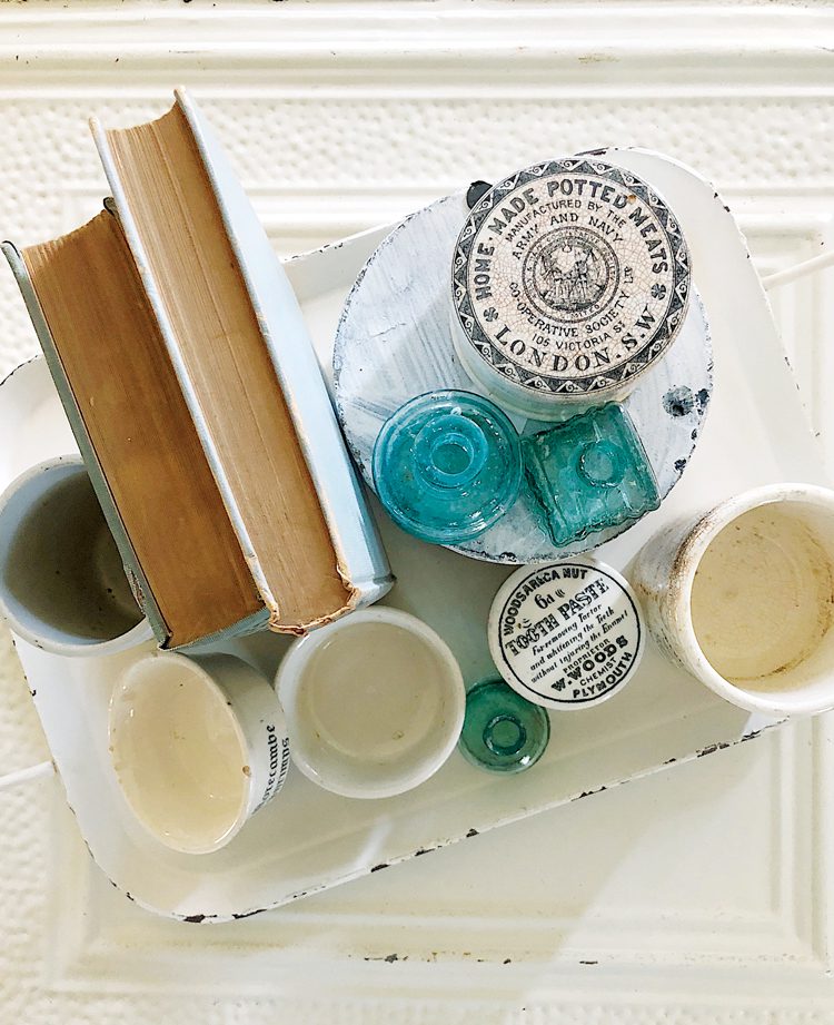 A view from above of two antique books beside several English advertising pots