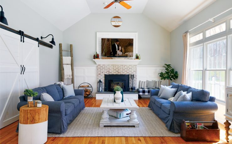 A modern farmhouse with white interior space and two large blue counchs facign each other.