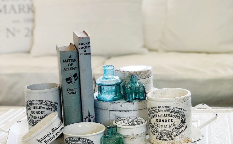 A coffee table sports a collection of English advertising pots with vintage farmhouse style