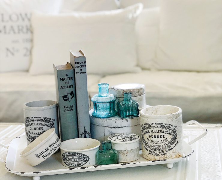 A coffee table sports a collection of English advertising pots with vintage farmhouse style