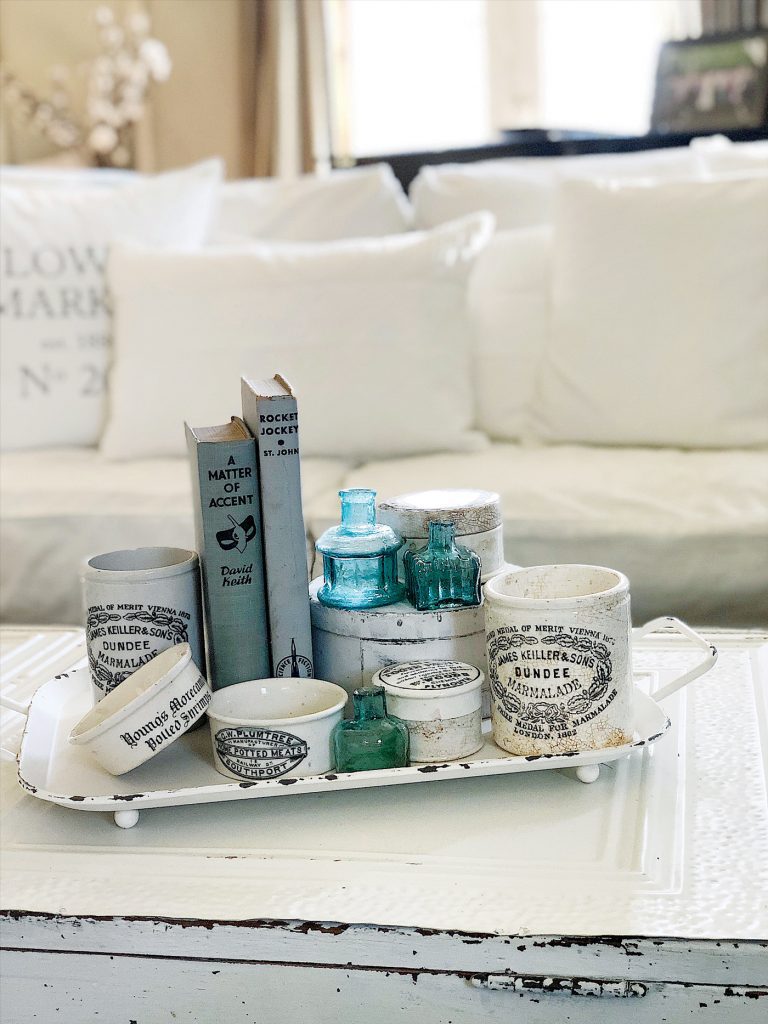 A coffee table sports a collection of English advertising pots with vintage farmhouse style