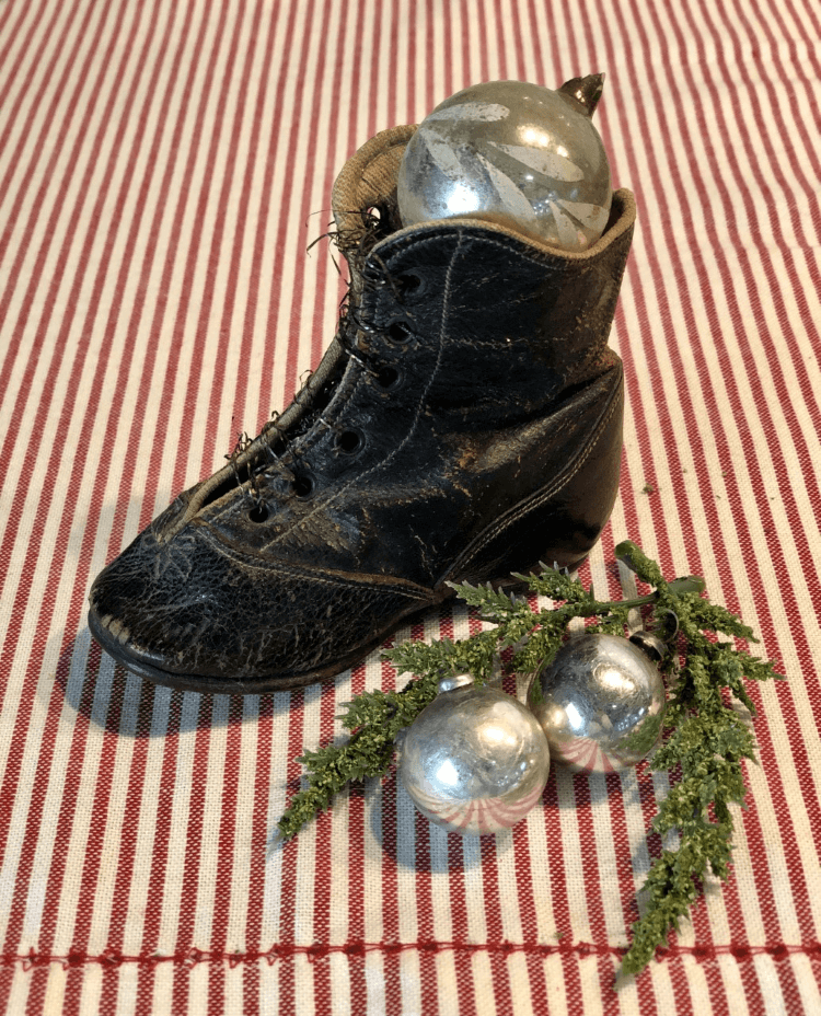 An antique tiny child's shoe with silver vintage Christmas ornaments inside