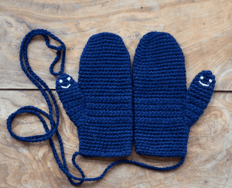 Blue mittens in yarn and sown together on a string. Happy faces appear on each thumb of the mittens.