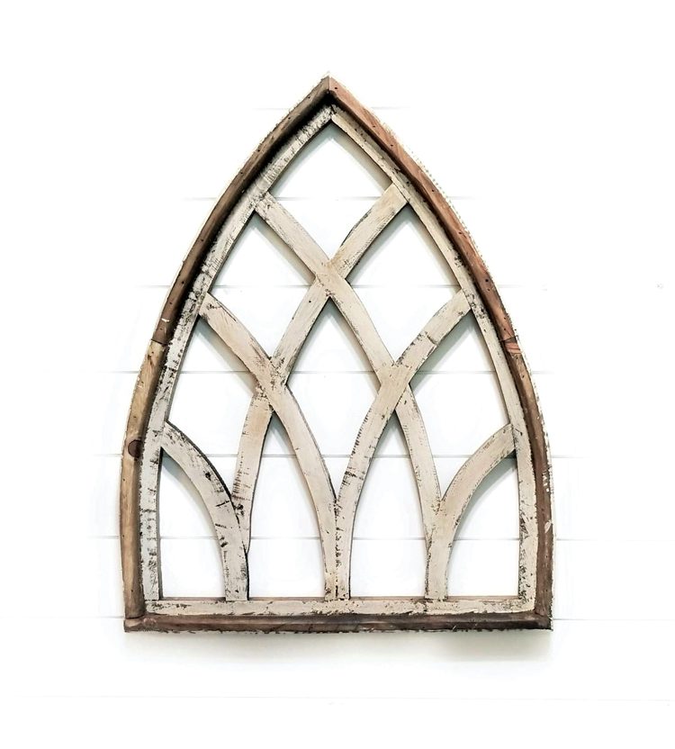A shabby-chic farmhouse wooden wall cathedral window in chippy white paint. The window is outlined with a bare wood frame.