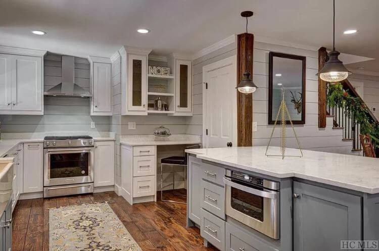 Kitchen with white shiplap wall paneling, painted white cupboards, and quartz countertops