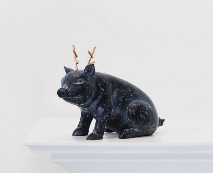 A metal pig figurine with gold reindeer antlers