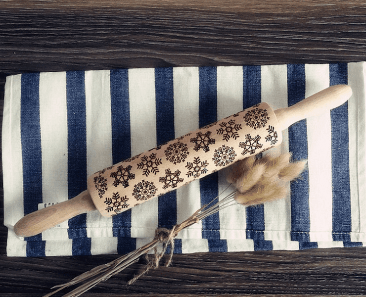A rolling pin with indents that make an intricate snowflake design with rolled on dough