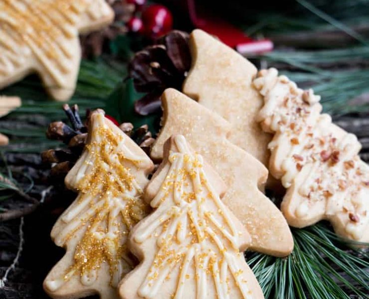 Caramel iced brown sugar cookies in tree shapes with golden sugar sprinkles