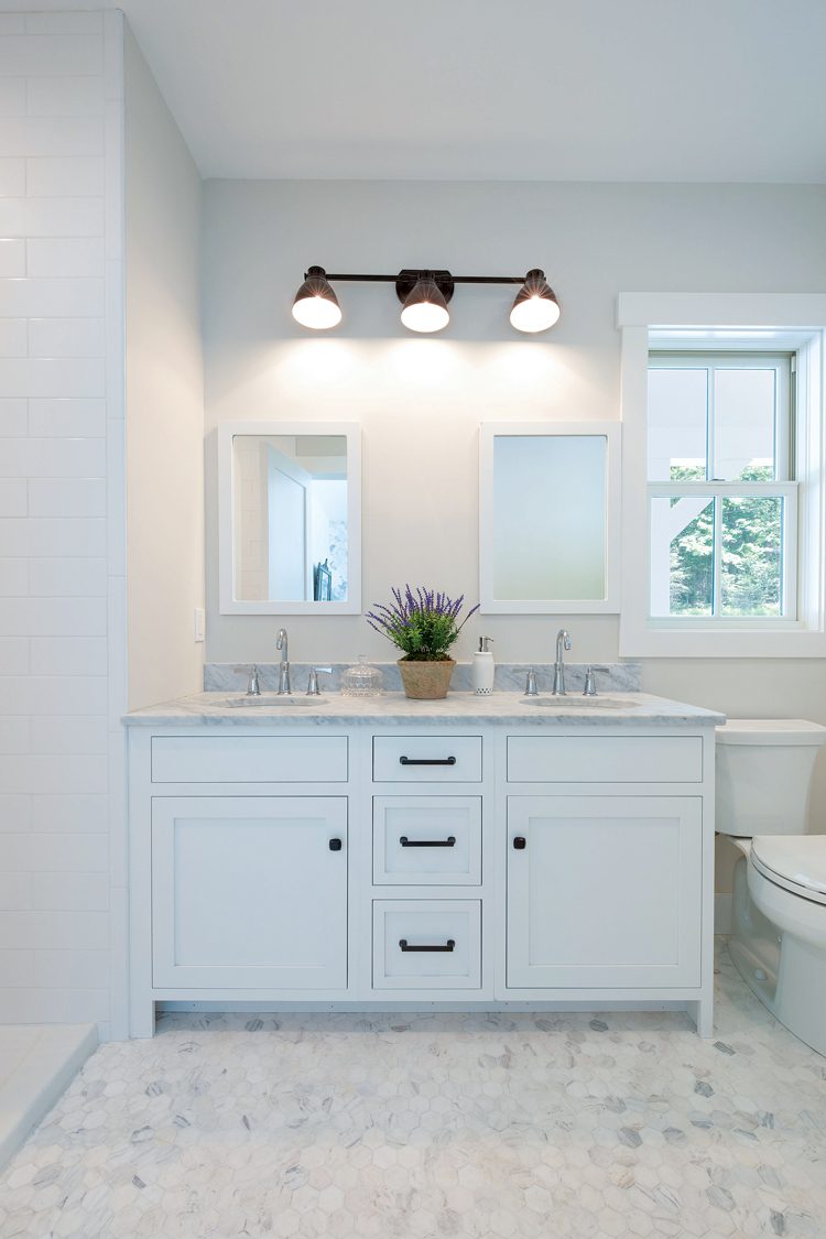 The bathroom has hexagon shaped tile in hues of gray and white